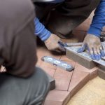 Closeup,Of,Man,Measuring,A,Red,Brick,Paver,For,Cutting